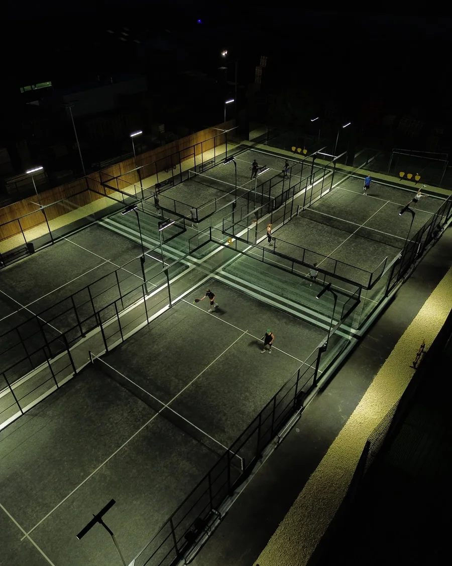 The four outdoor courts at Pukka Padel Leeds at dusk, floodlit, from above.